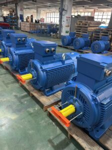Several large blue industrial motors lined up in a factory setting.